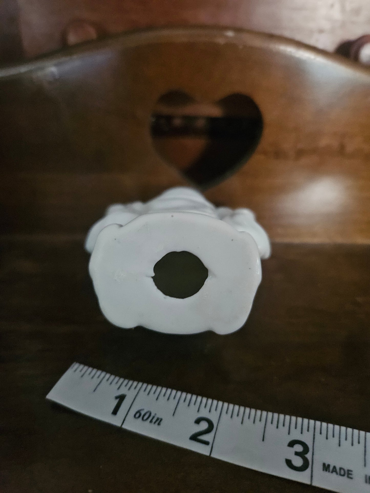 Bottom of white porcelain Laughing Buddha figurine showing open unglazed drain hole
