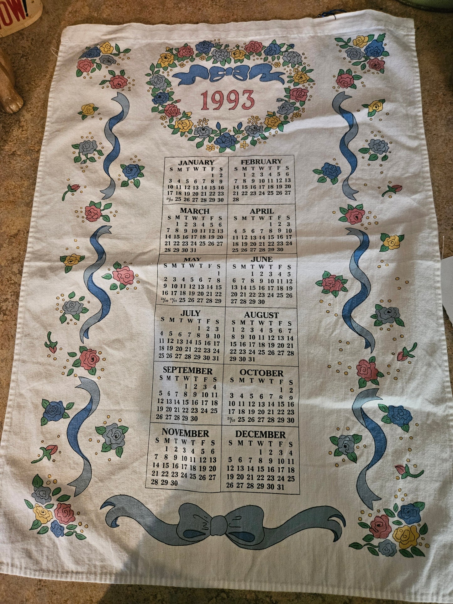 1993 calendar linen tea towel with roses, blue ribbons, and floral wreath border