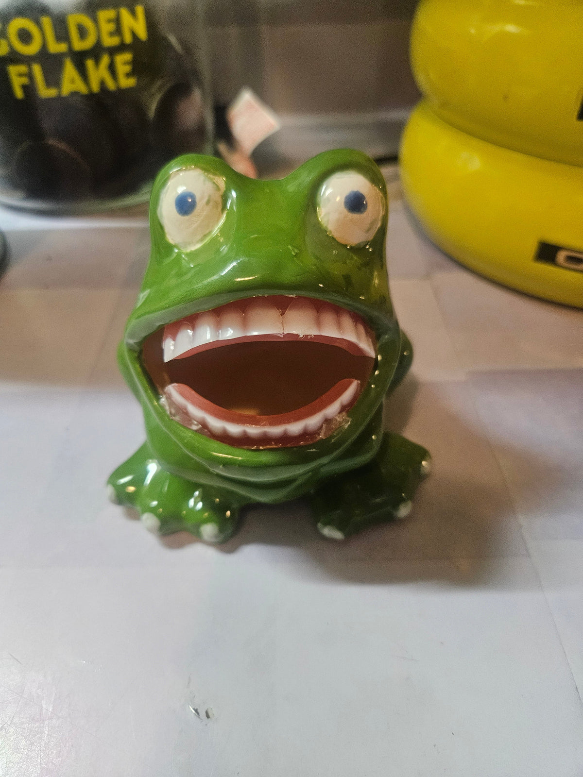 Ceramic sponge frog figurine viewed from behind, showing glossy green glaze and seated pose
