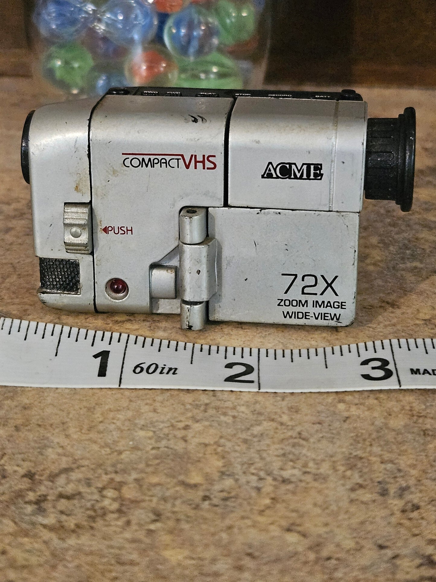ACME Compact VHS miniature camcorder side view showing 72X Zoom Wide-View label with ruler for scale