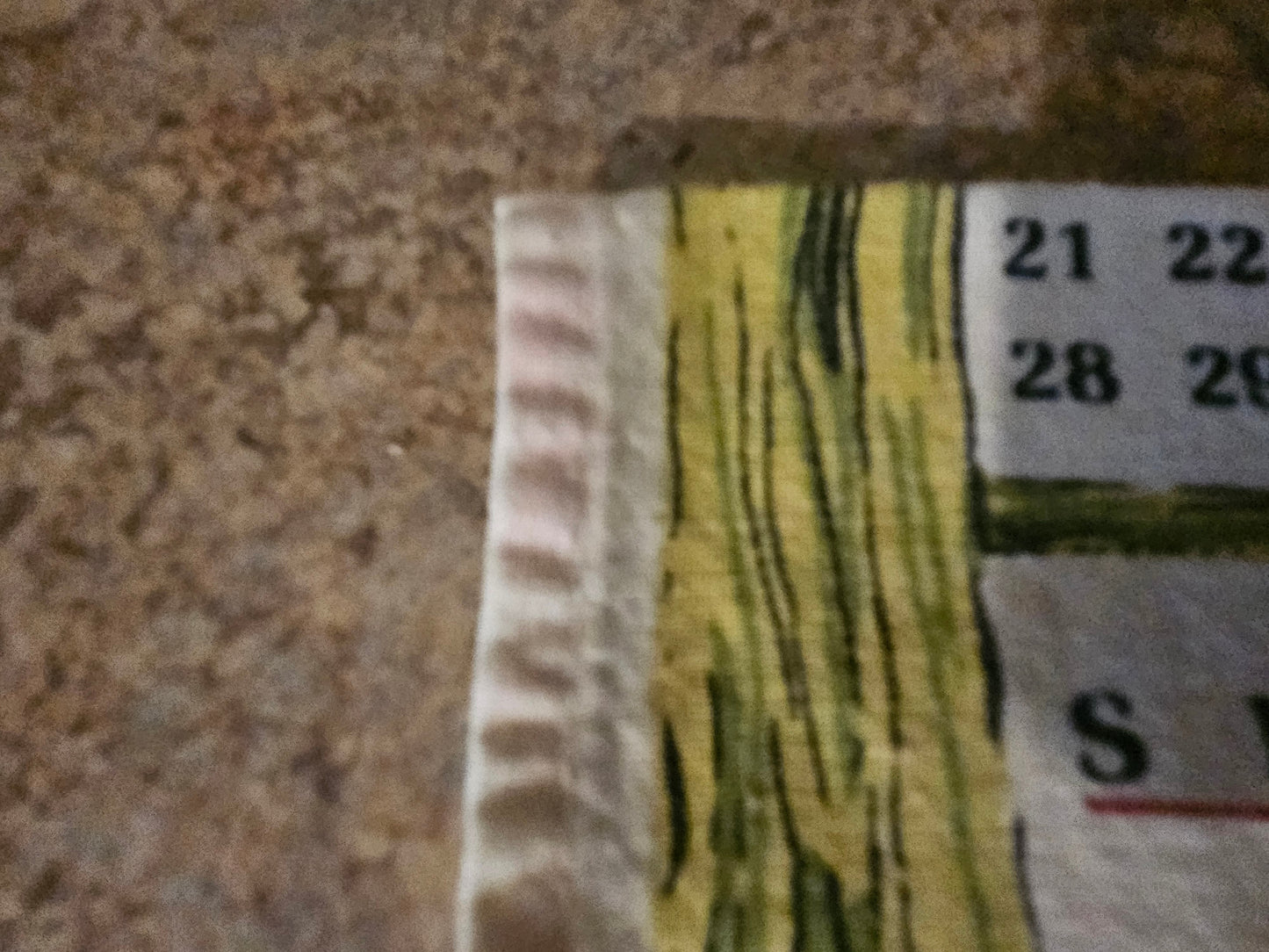 Close-up of hemmed edge and wood-grain border detail on 1968 calendar towel
