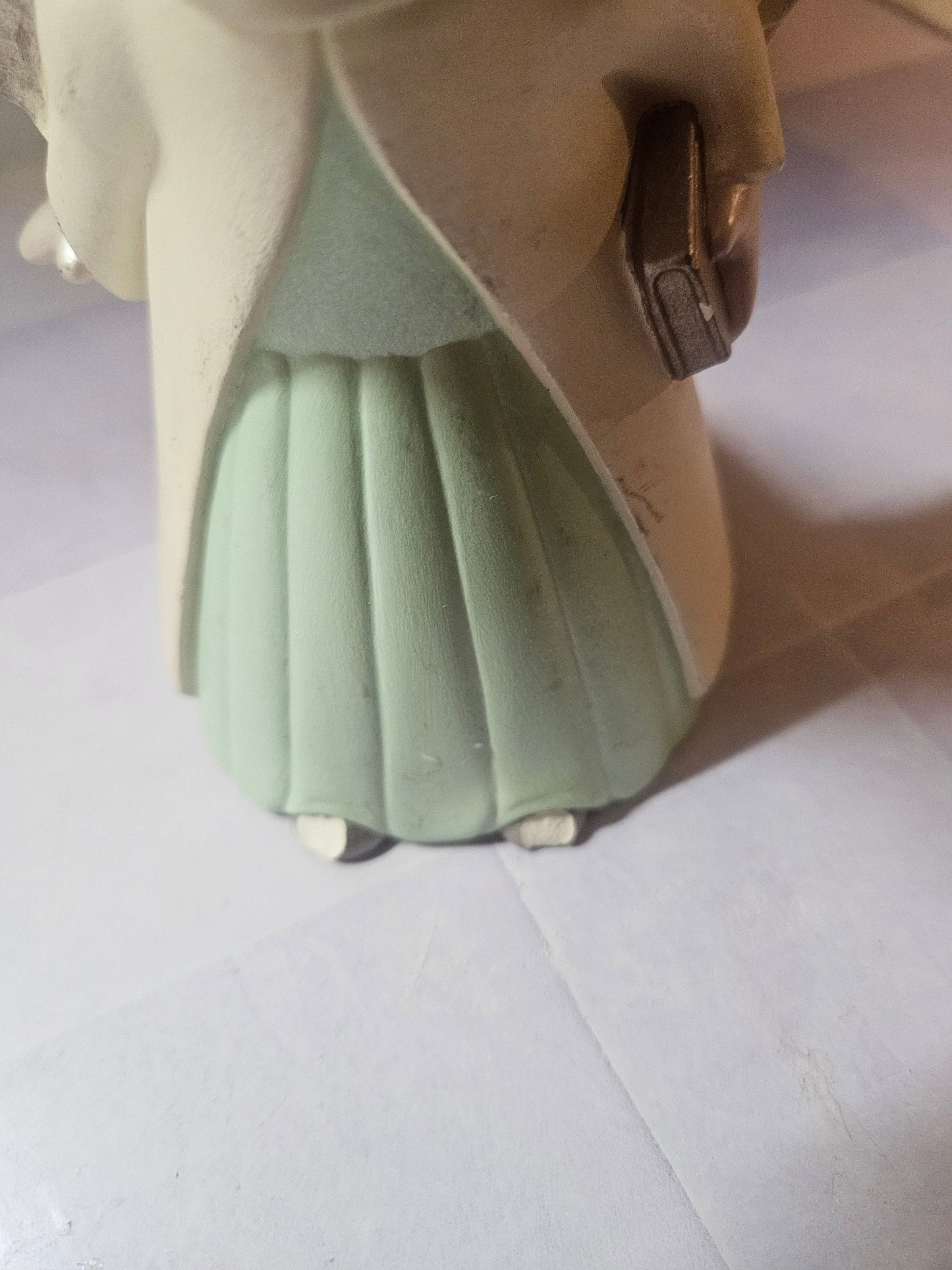 Close-up of mint green pleated dress hem and small white feet