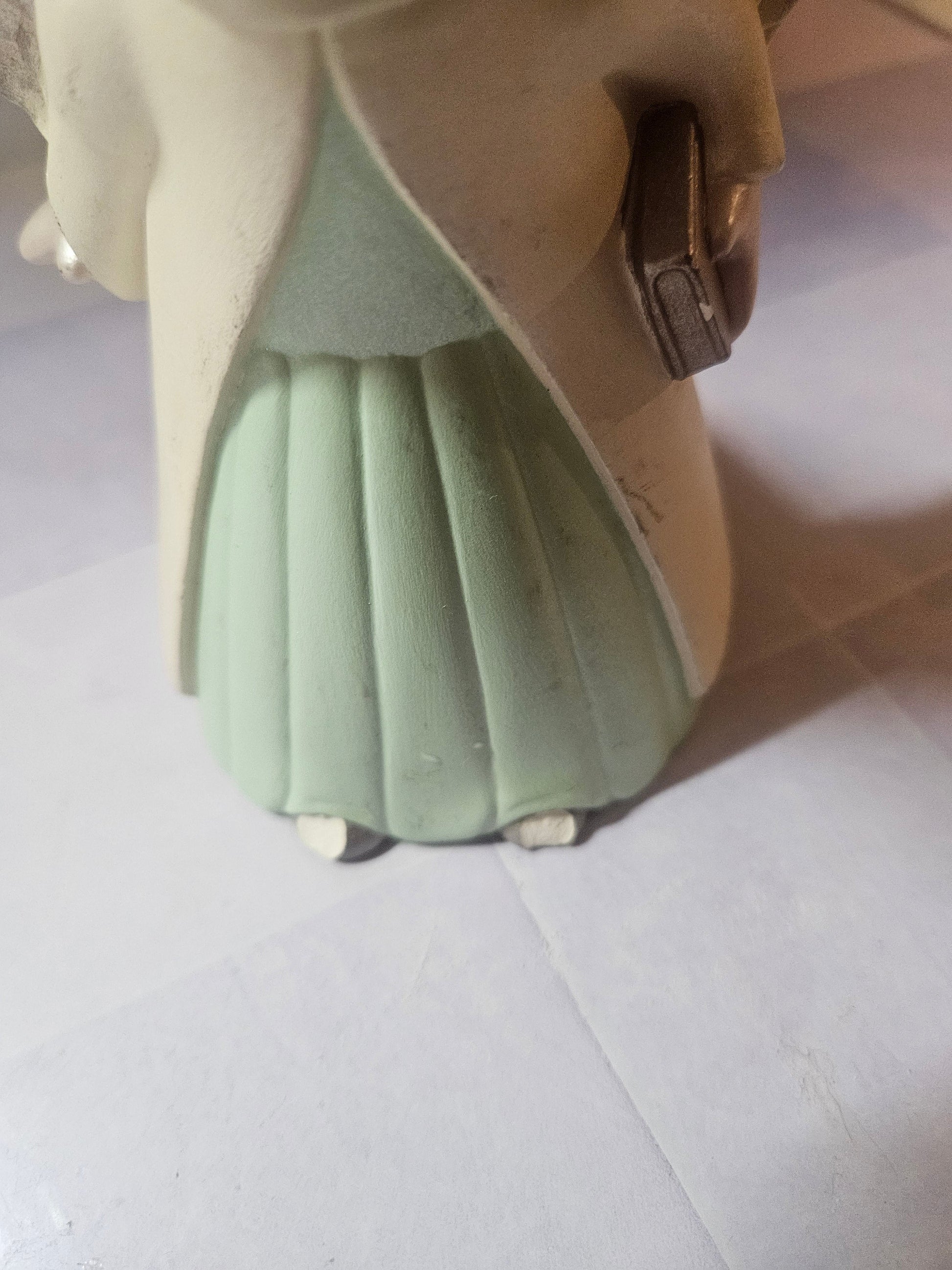 Close-up of mint green pleated dress hem and small white feet