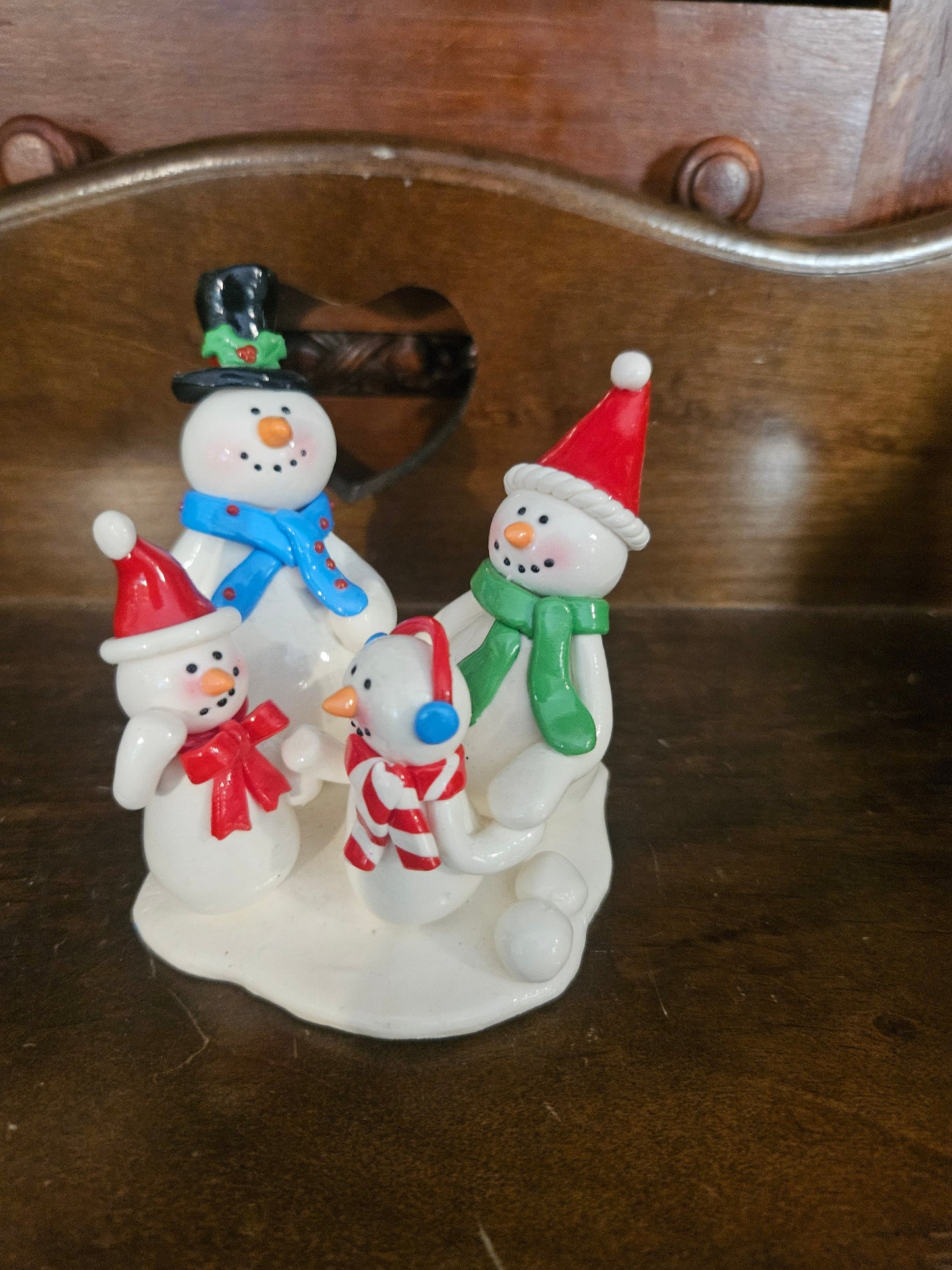 Vintage ceramic snowman family figurine with four snowmen on snowy base, dad in top hat, mom in red Santa hat, two children
