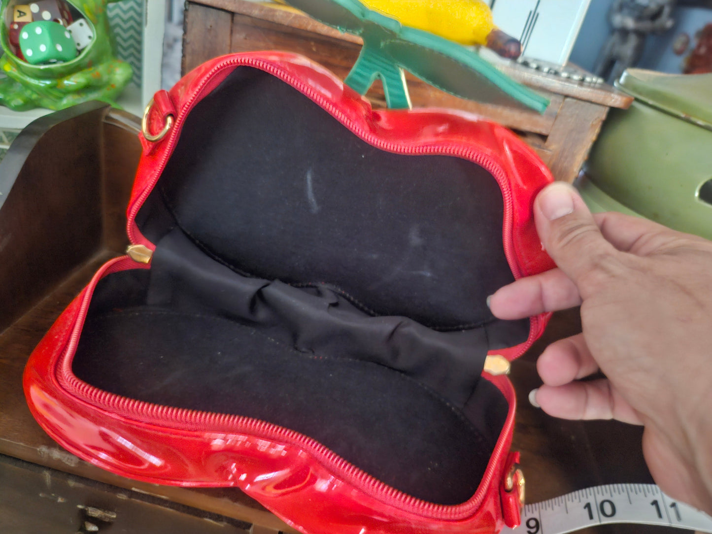 Interior of red patent cherry bag open showing black fabric lining and interior zip pocket