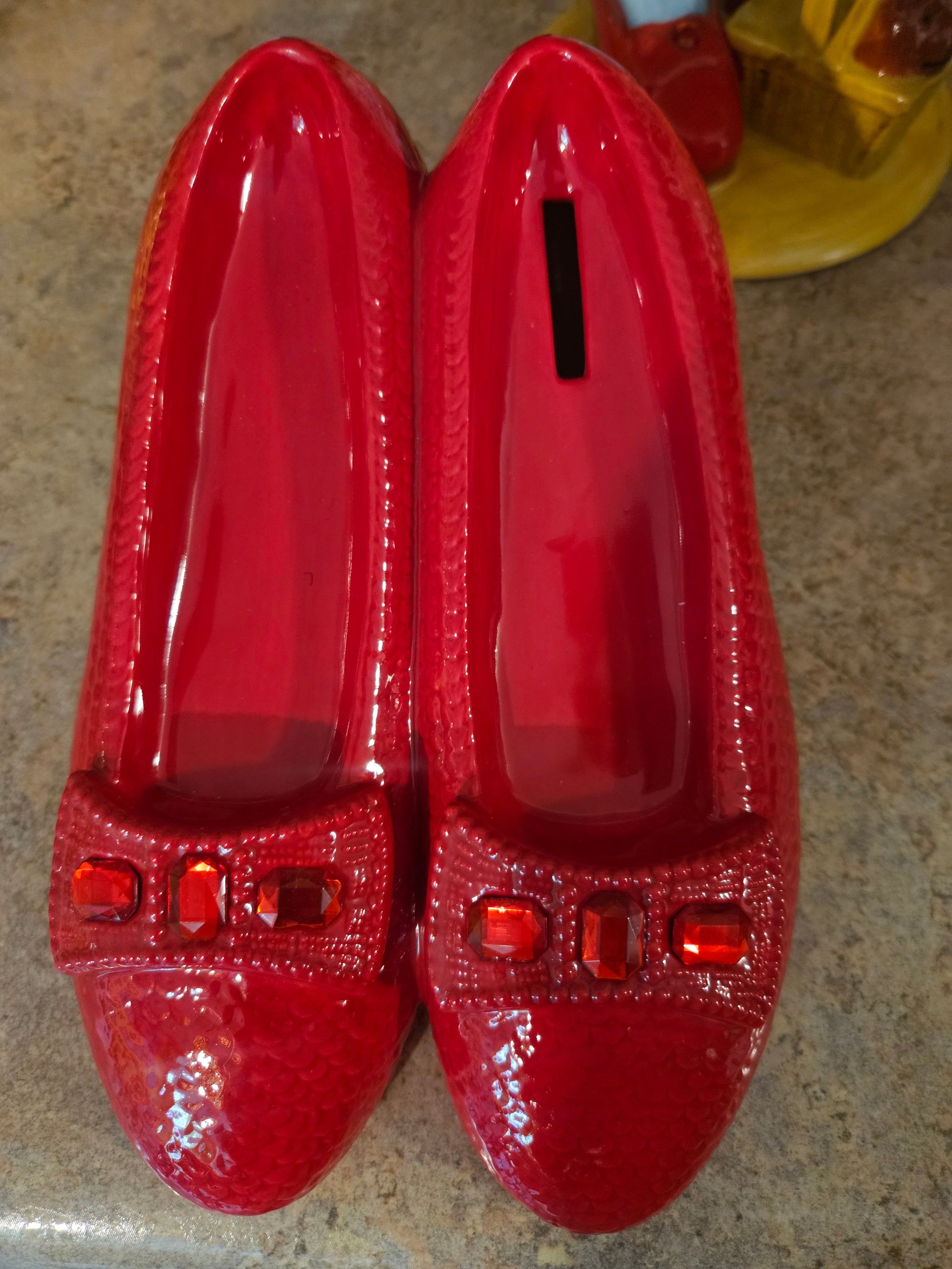 Wizard of Oz Ruby Slippers ceramic coin bank by Westland Giftware showing glossy red glaze and red rhinestone jewel toe accents