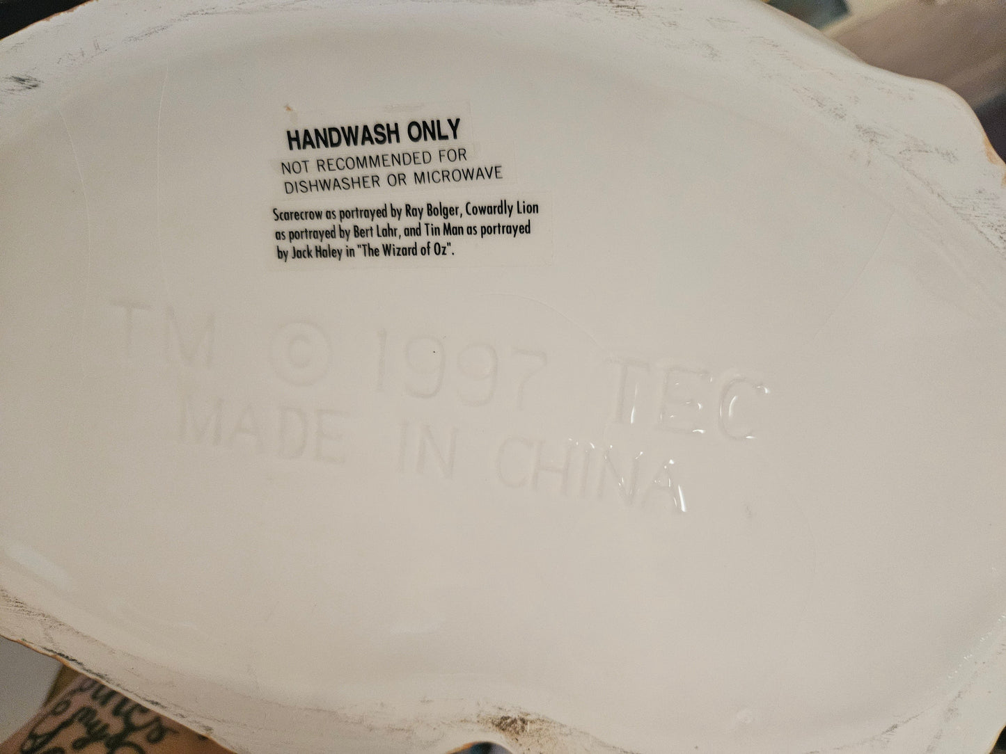 Bottom of Wizard of Oz triple face cookie jar showing actor attributions Ray Bolger Bert Lahr Jack Haley and handwash care instructions