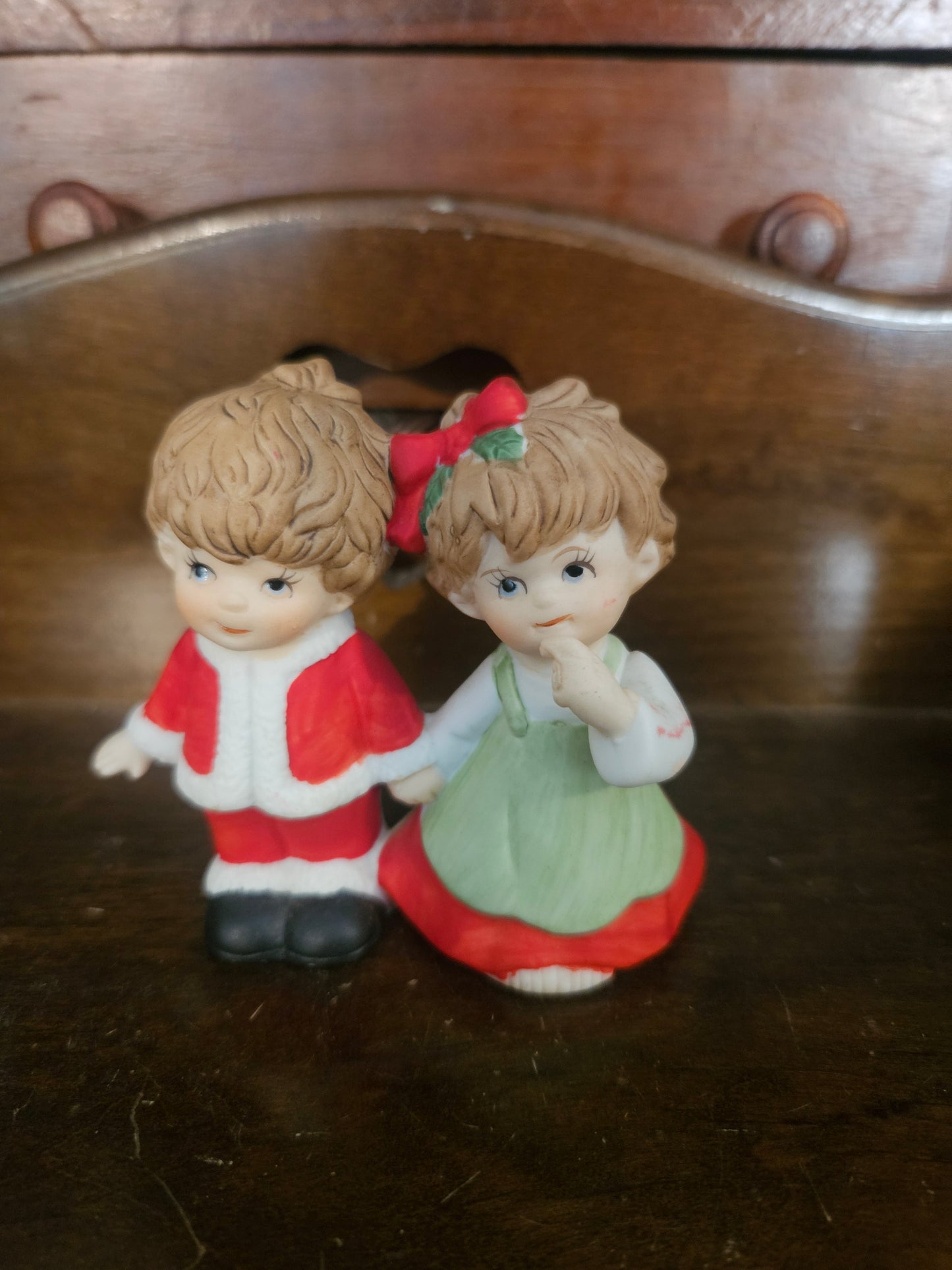 Vintage ceramic Christmas boy and girl figurines, boy in red Santa suit and girl in green dress with holly bow