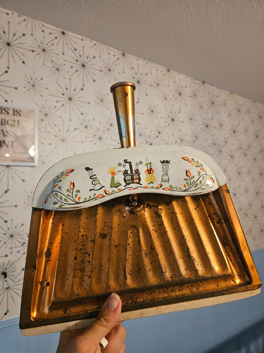 Vintage JV Reed tin dustpan with Pennsylvania Dutch folk art decoration showing wood stove figures and tulip motifs on white header with brass handle