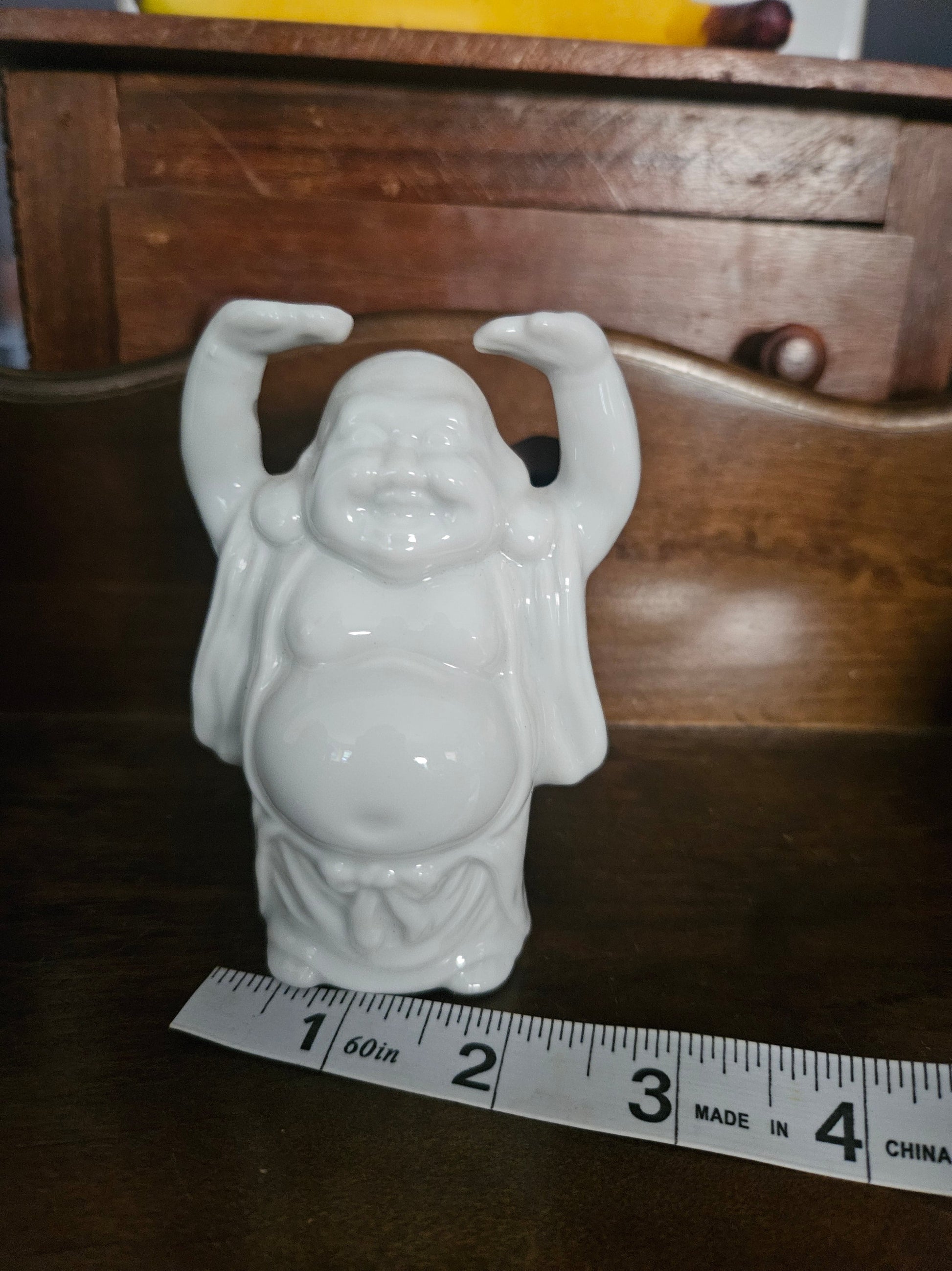 White porcelain Laughing Buddha Budai figurine with arms raised, front view with ruler showing approximately 3 inches tall