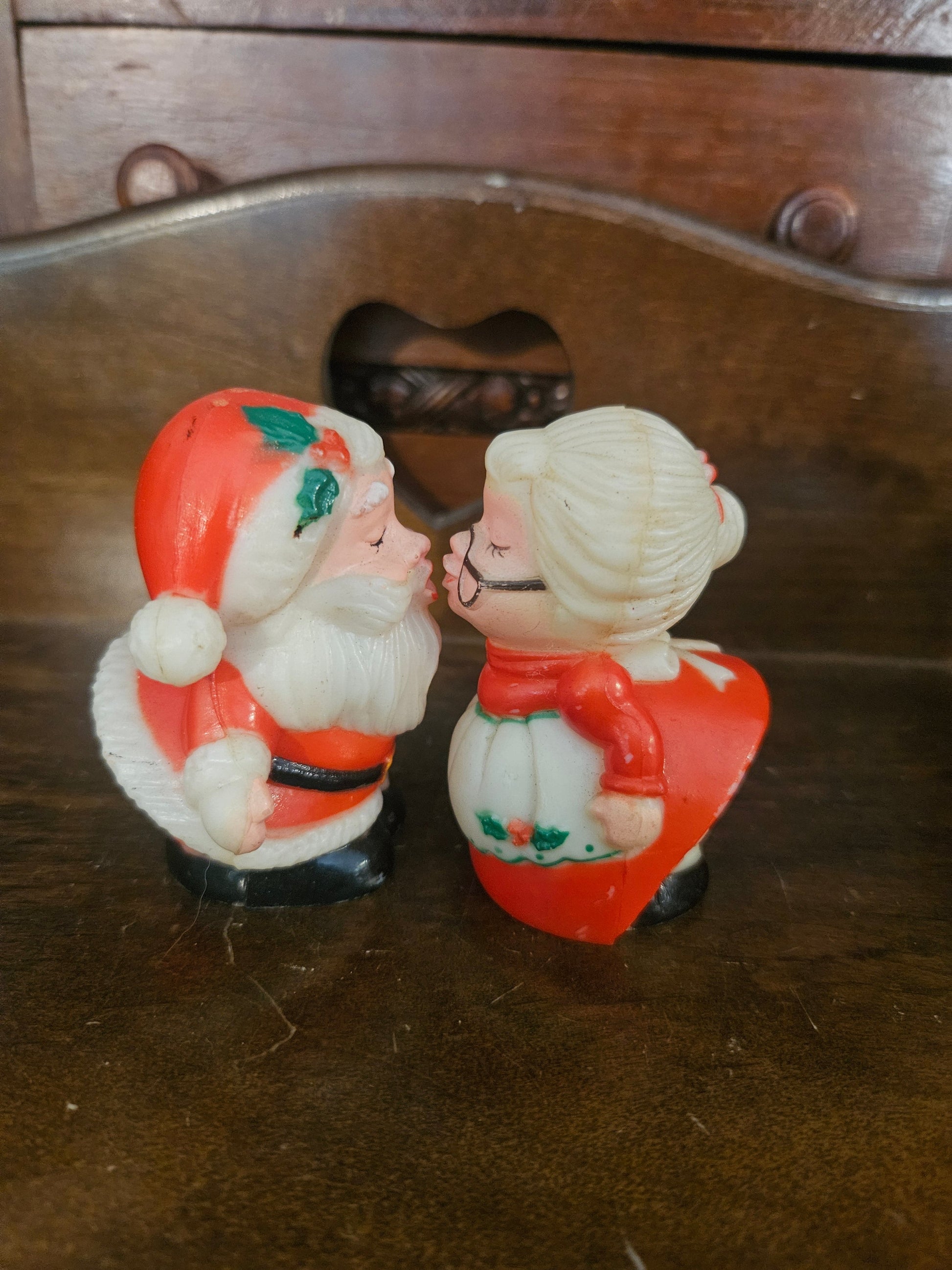 Vintage plastic kissing Santa and Mrs. Claus salt and pepper shakers facing each other on wooden surface