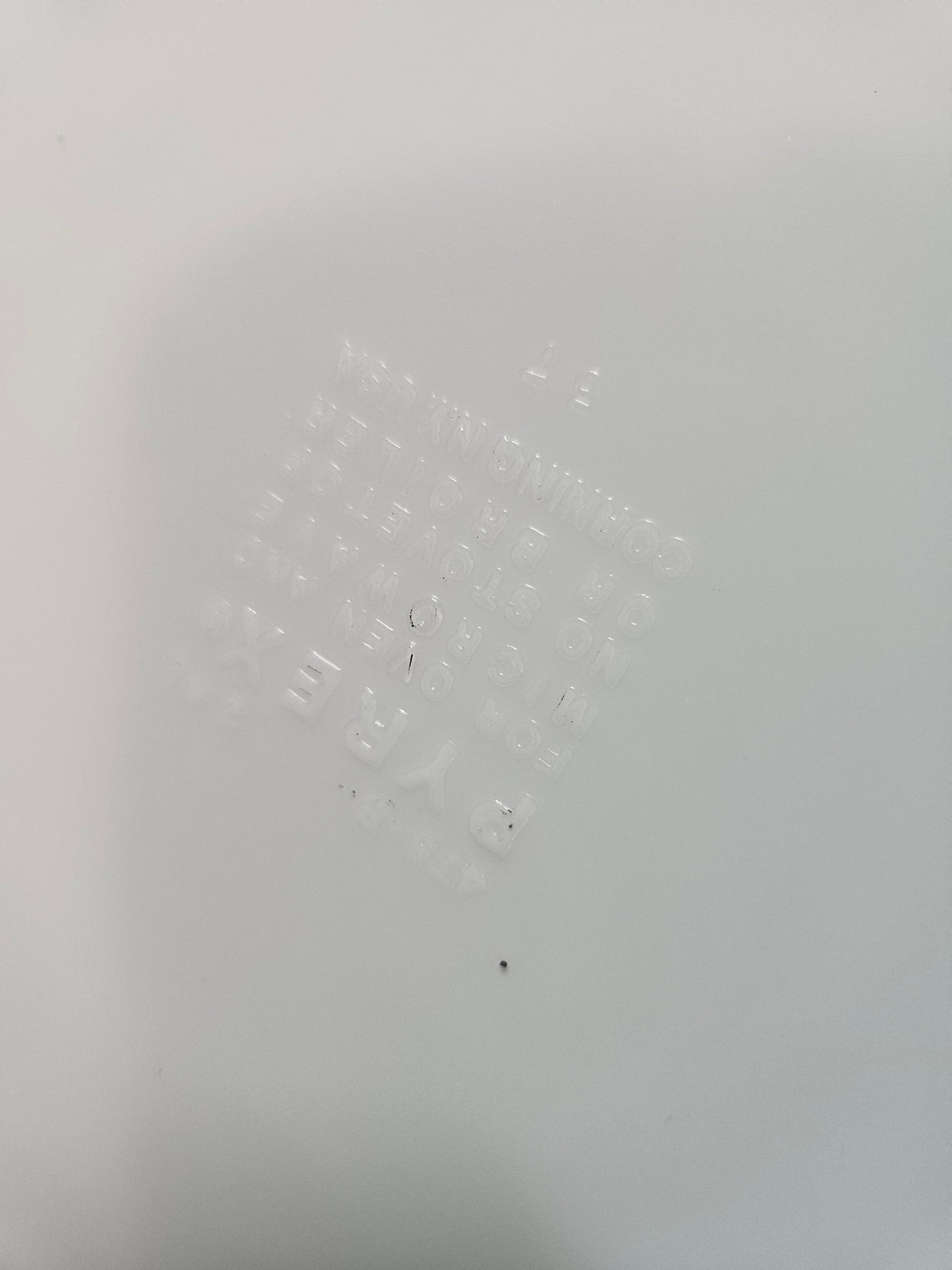 Close-up of a faint, illegible Pyrex bottom stamp