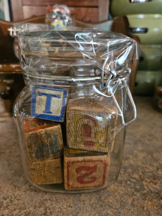 Swing-top glass jar filled with vintage wooden alphabet blocks, closed view