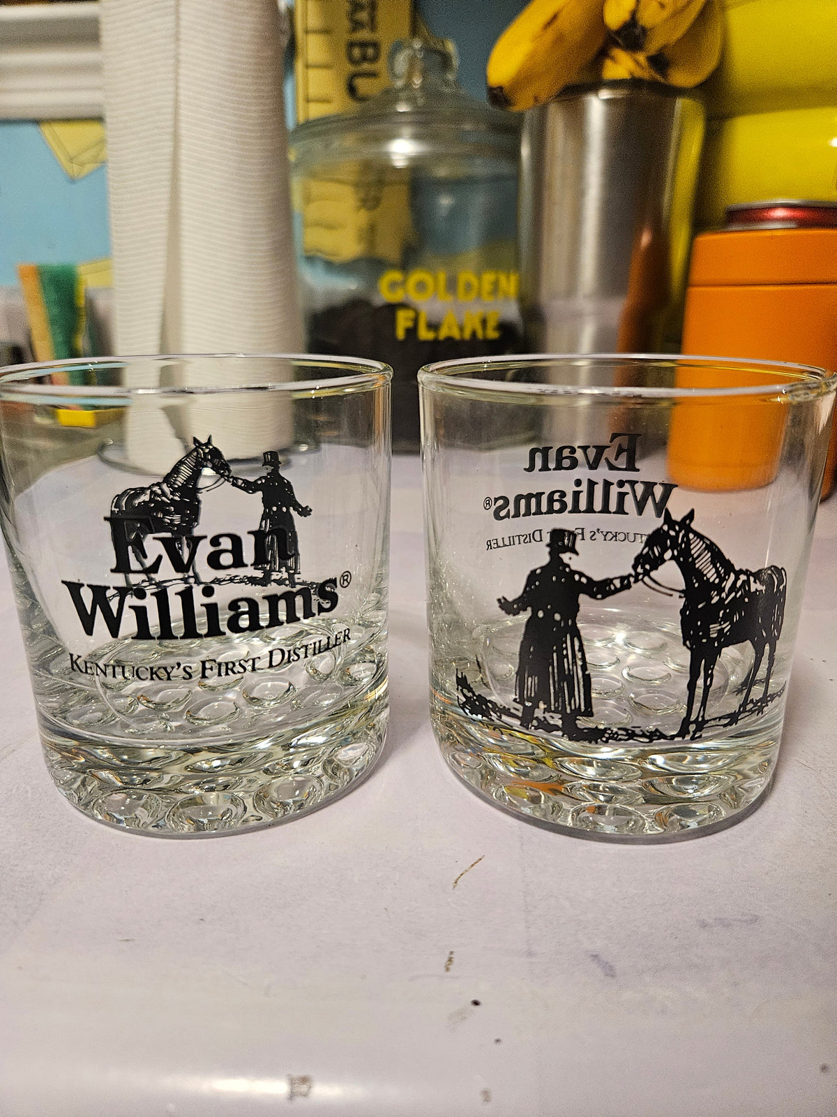 Two Evan Williams bourbon rocks glasses with horse and handler graphics