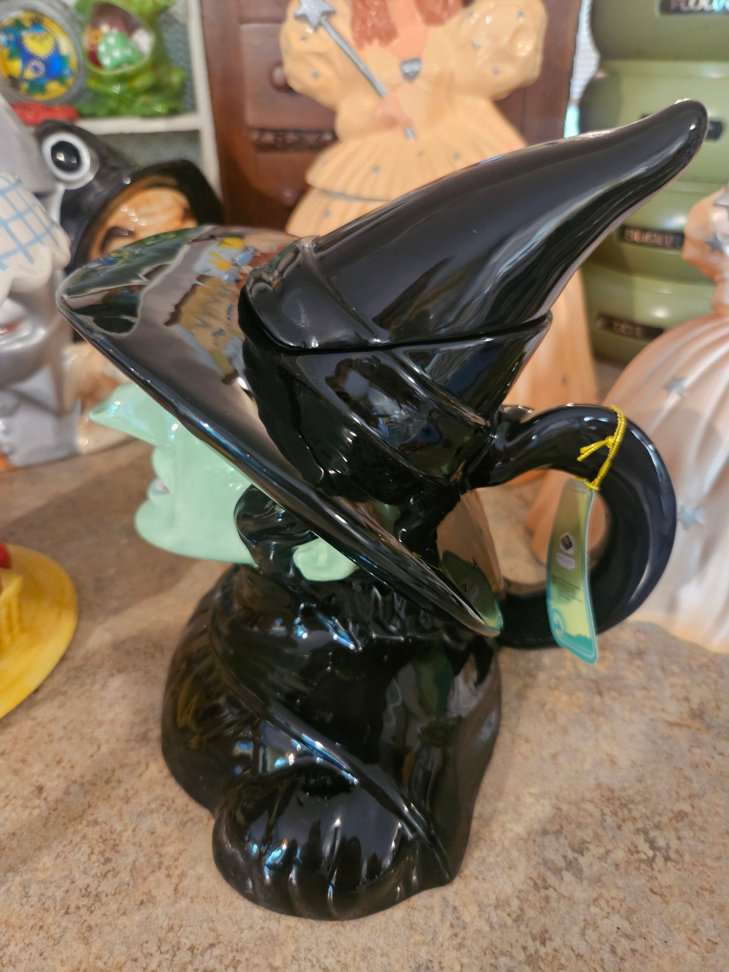 Side view of Wicked Witch teapot showing broomstick handle and original Westland Giftware hang tag attached