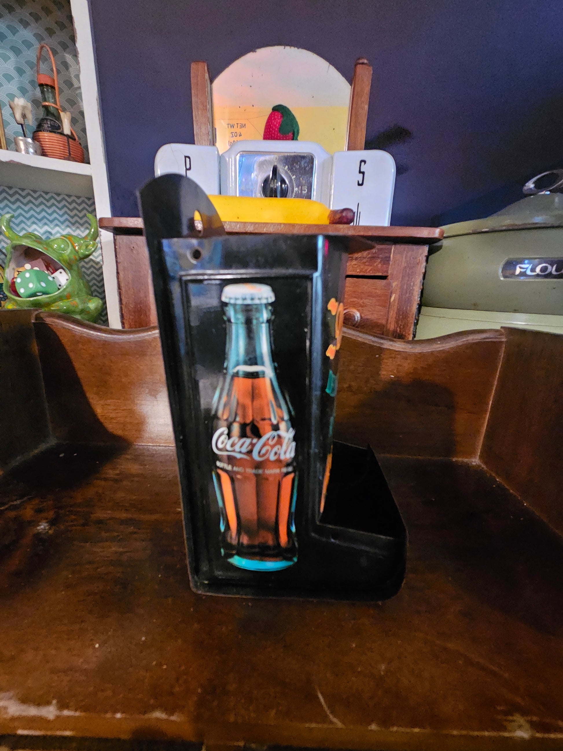 Angled view of Coca-Cola napkin holder showing contour bottle side graphic and top tray
