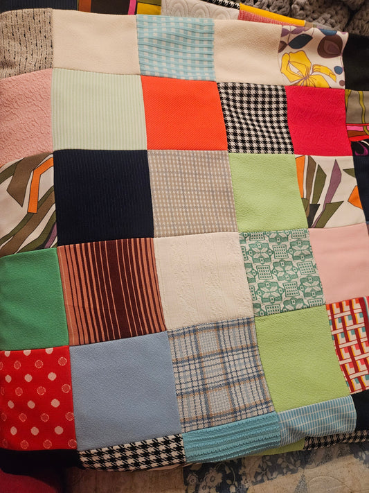 Vintage handmade patchwork quilt showing large mixed fabric squares including houndstooth, corduroy, knit, and floral prints