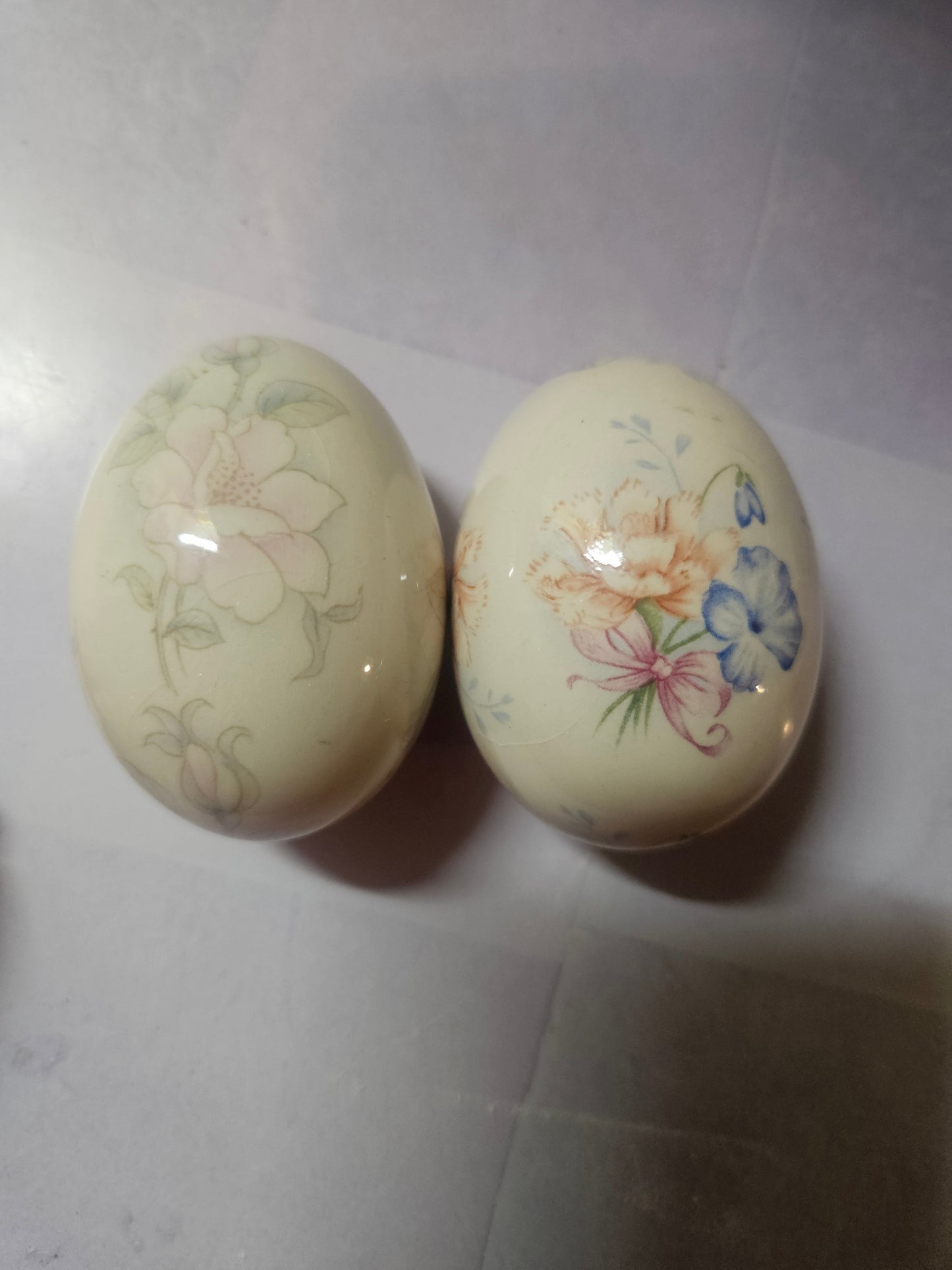Two hand-painted porcelain floral eggs by The Egg Lady — pink blossom and lily iris designs