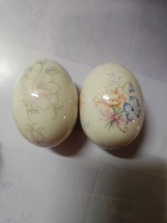 Two hand-painted porcelain floral eggs by The Egg Lady — pink blossom and lily iris designs