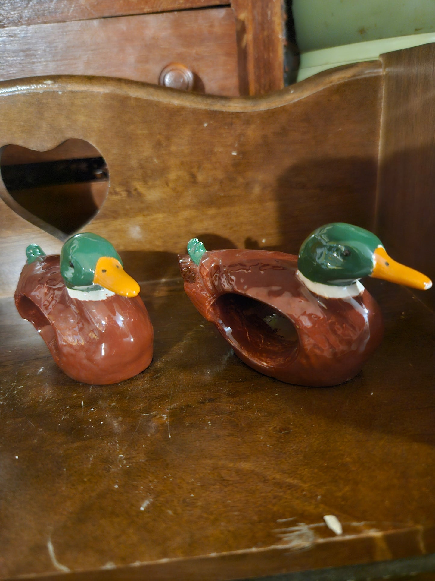 Pair of mallard duck ceramic napkin rings showing green heads, yellow beaks, and brown glazed bodies