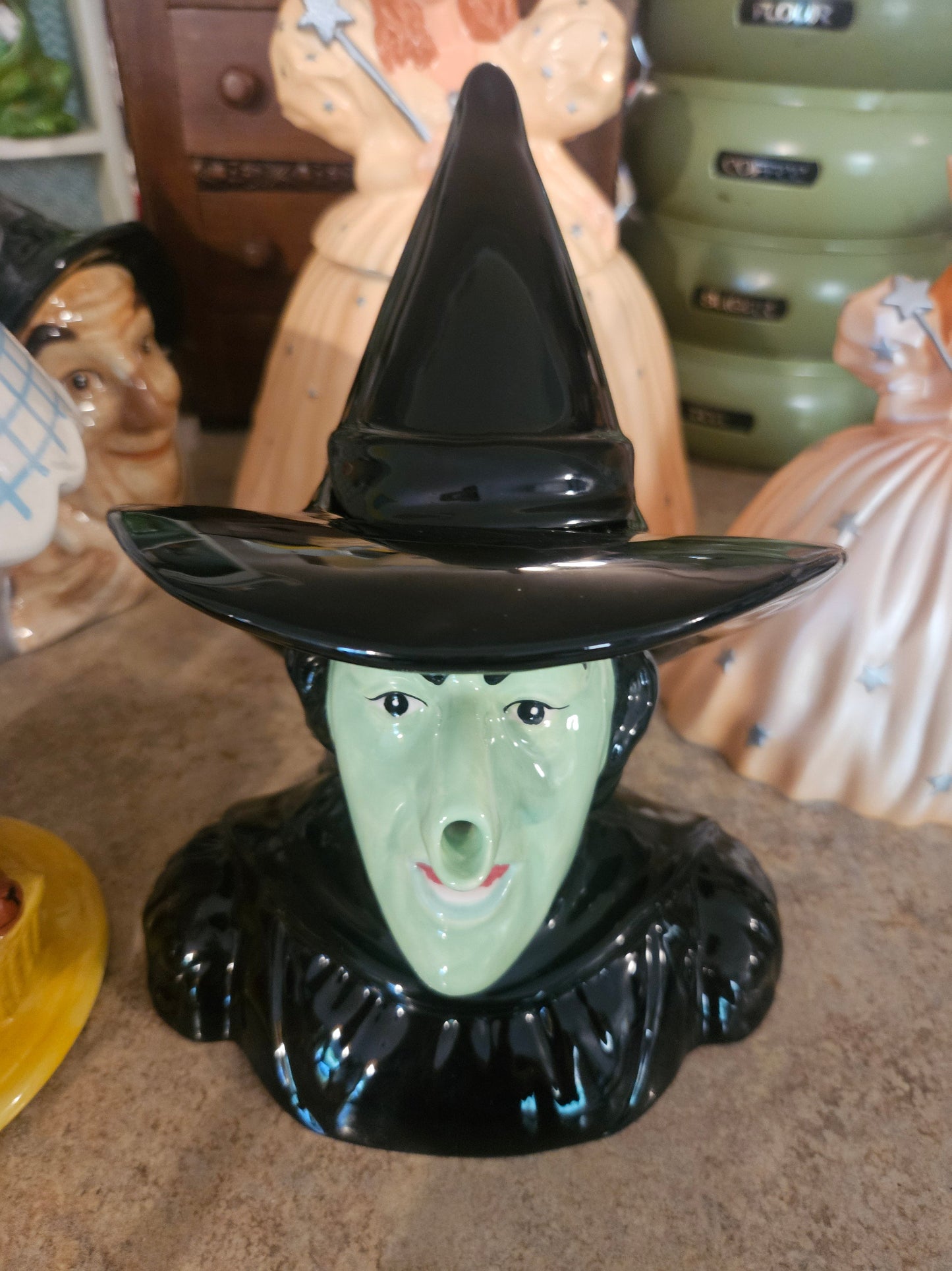 Westland Giftware Wizard of Oz Wicked Witch of the West ceramic teapot front view showing green face black hat lid and broomstick handle