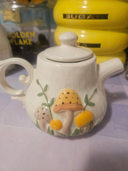 Vintage ceramic mushroom teapot front view showing 3D mushroom and yellow daisy relief on cream glaze