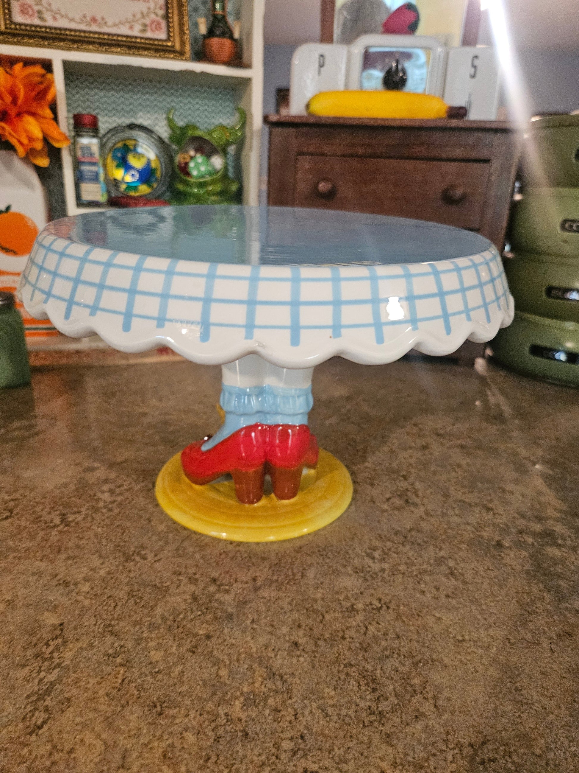 Side view of Dorothy legs cake stand showing blue stockings pedestal and yellow brick road base