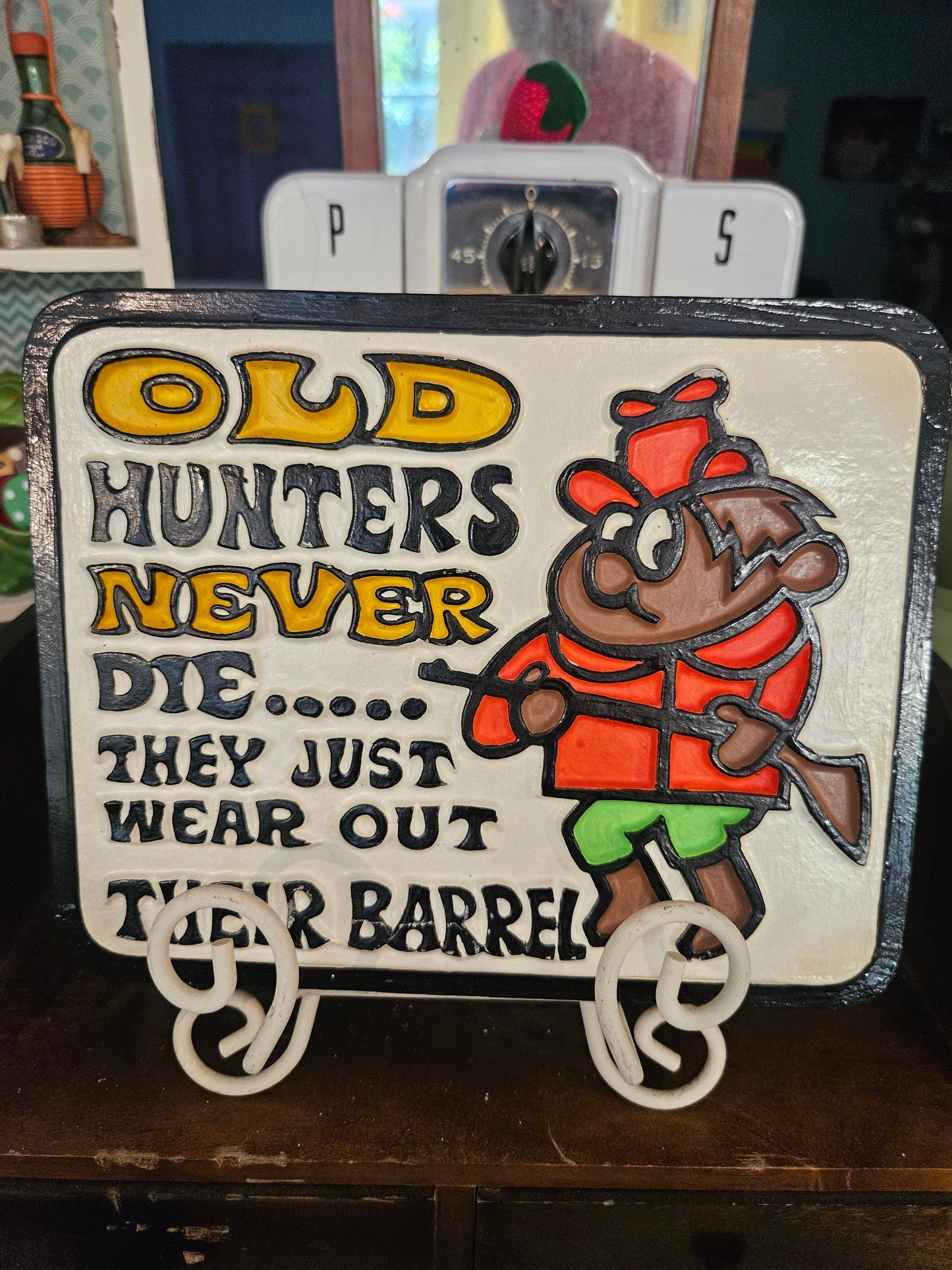 Front of vintage ceramic wall plaque reading Old Hunters Never Die They Just Wear Out Their Barrels with cartoon hunter