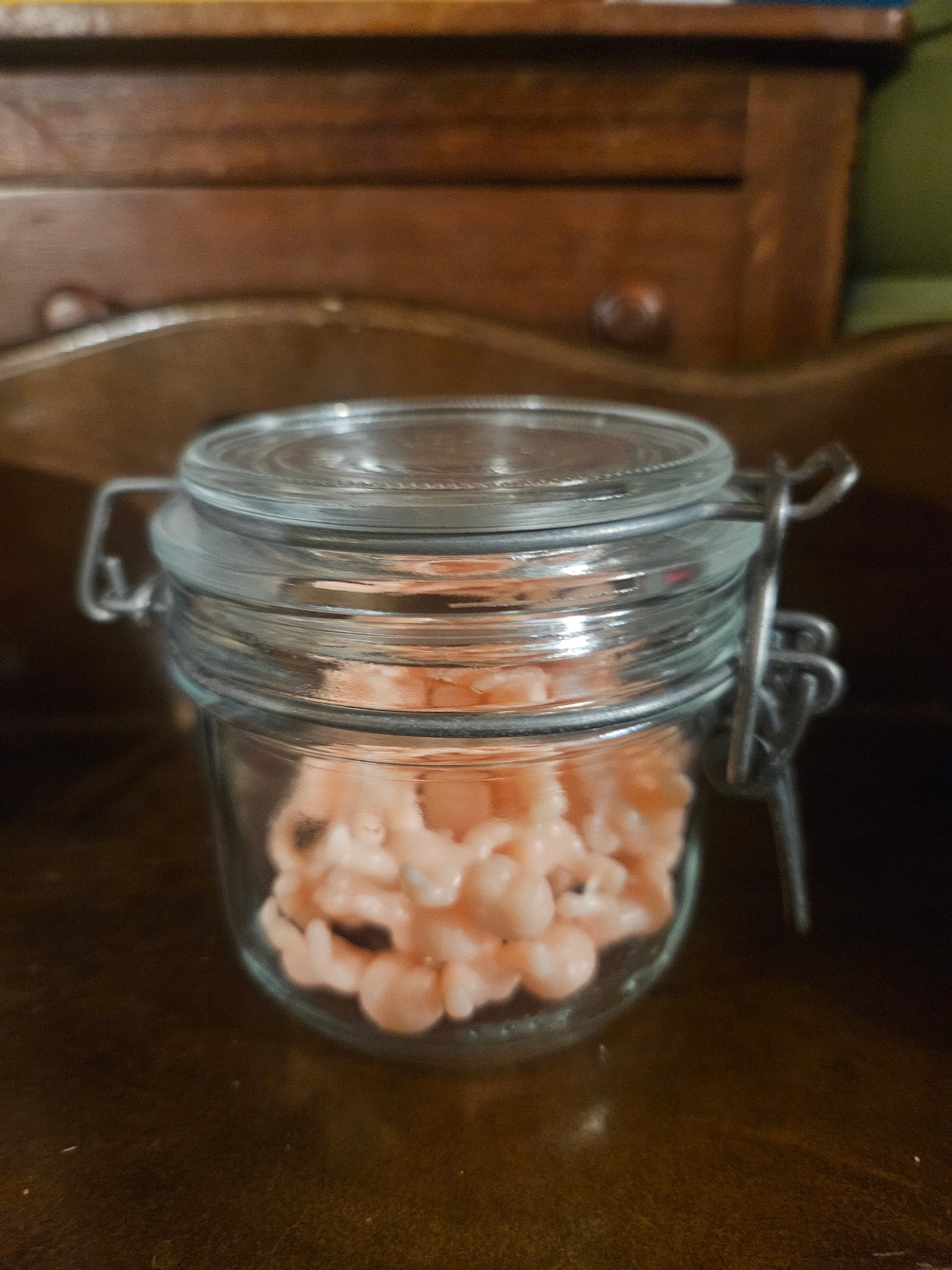 Swing-top glass jar filled with tiny pink plastic baby figurines, closed view