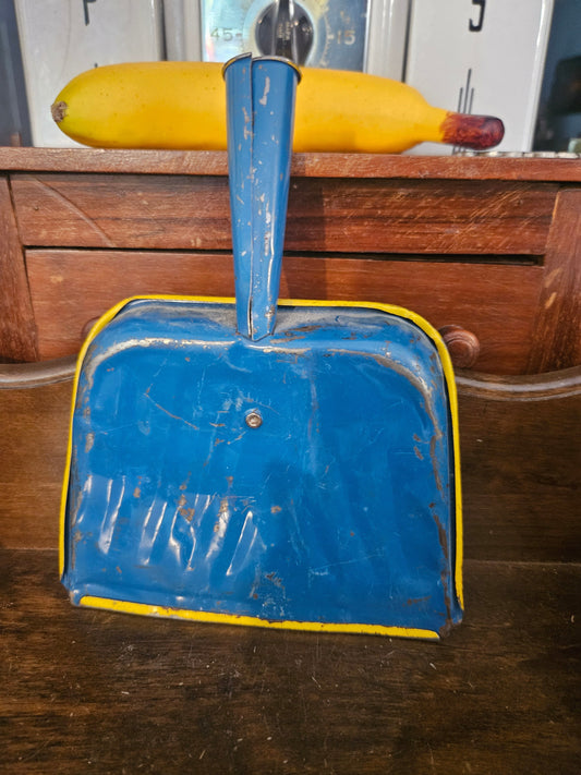Vintage tin dustpan back view showing cobalt blue exterior with yellow trim and riveted handle