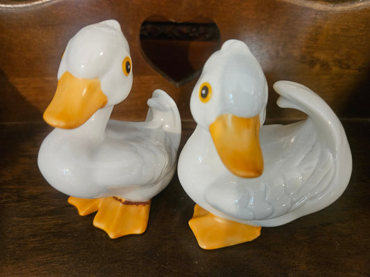 Pair of vintage ceramic white duck figurines with orange beaks and yellow glass eyes front view