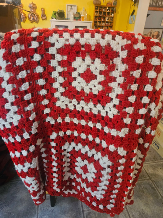 Vintage handmade red and white granny square crochet afghan draped over chair showing bold two-tone pattern