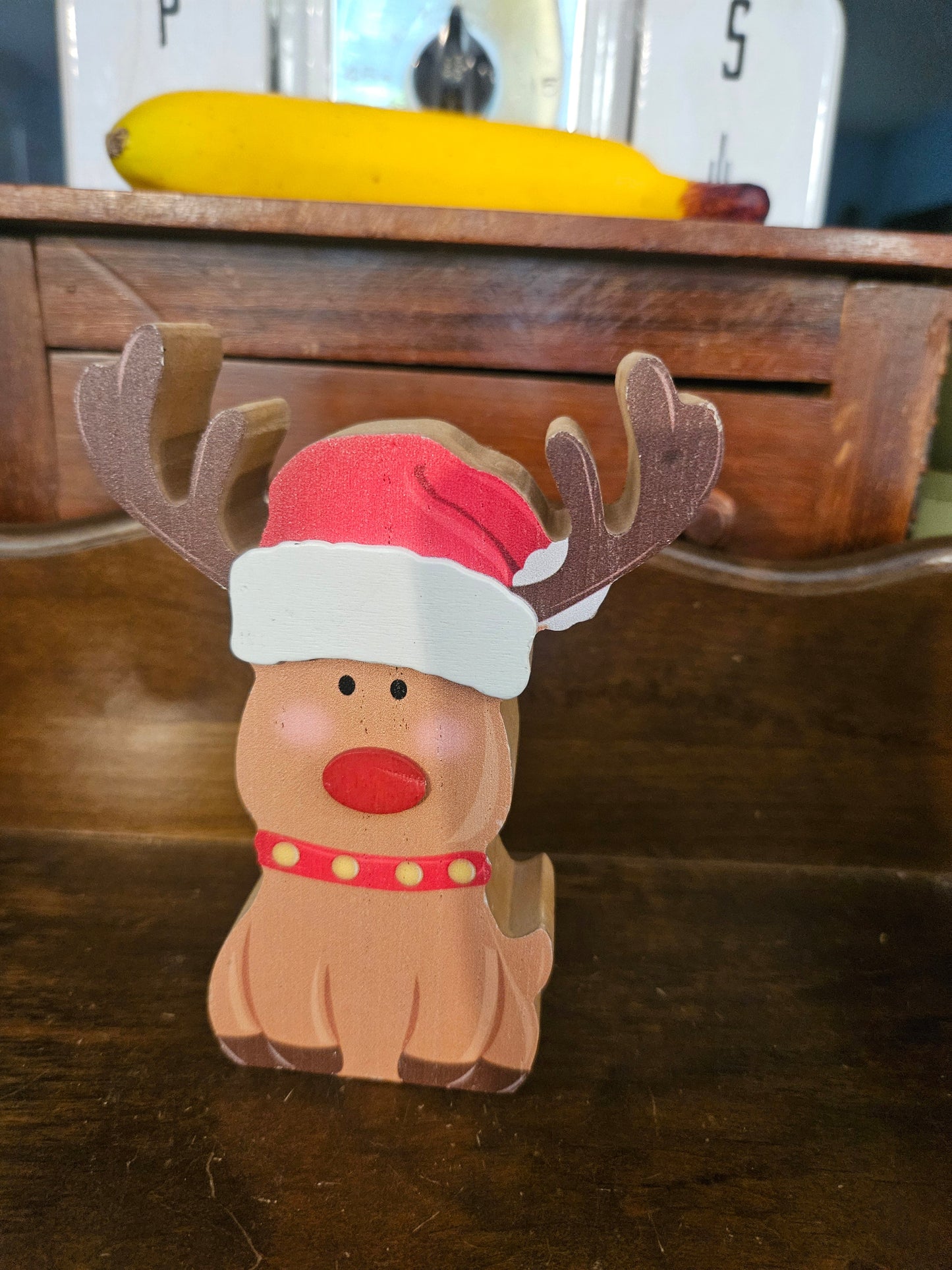 Vintage wooden Rudolph reindeer figurine with red nose, Santa hat, and polka-dot collar, approximately 5.5 inches tall