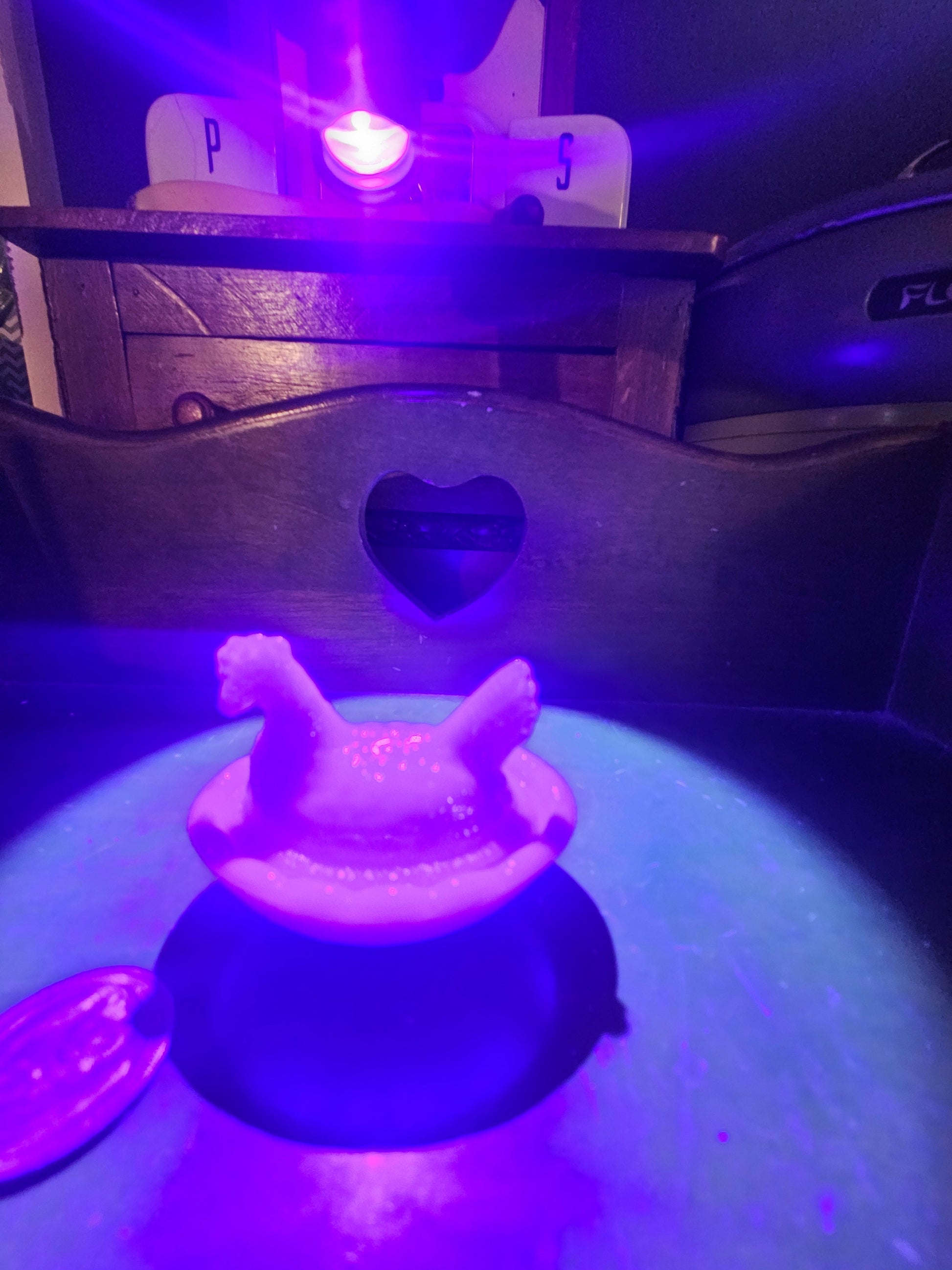 Blue slag glass hen on nest glowing purple and white under UV blacklight