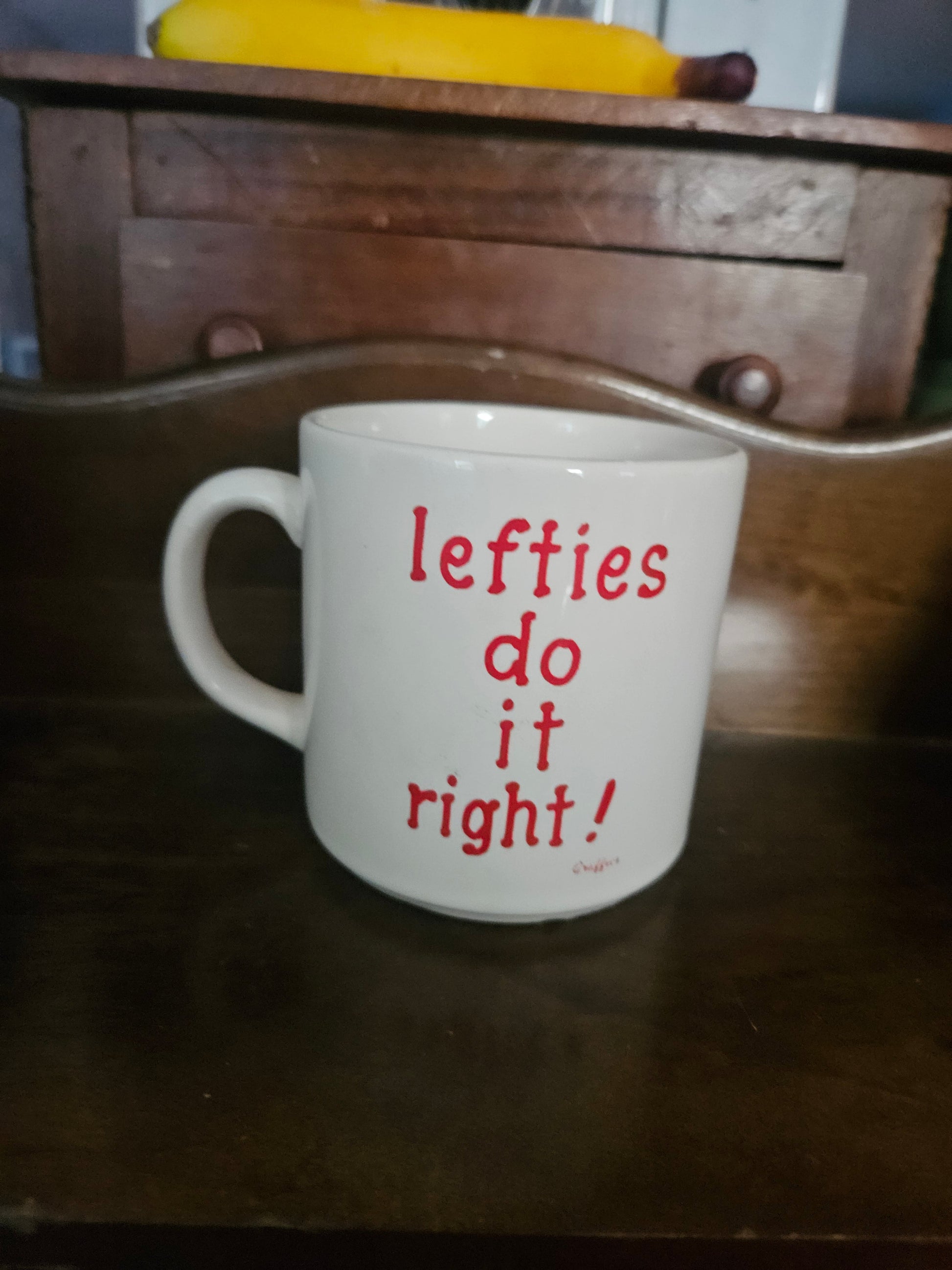 White ceramic mug with red hand-lettered text reading lefties do it right, front view