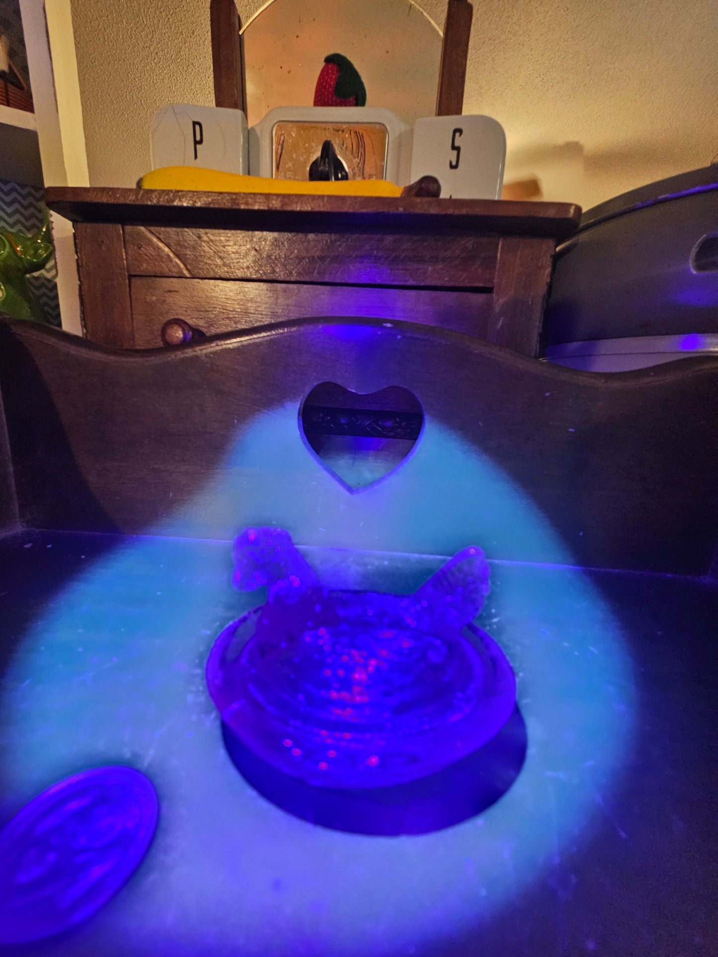 Iridescent carnival glass hen on nest glowing blue and purple under UV blacklight
