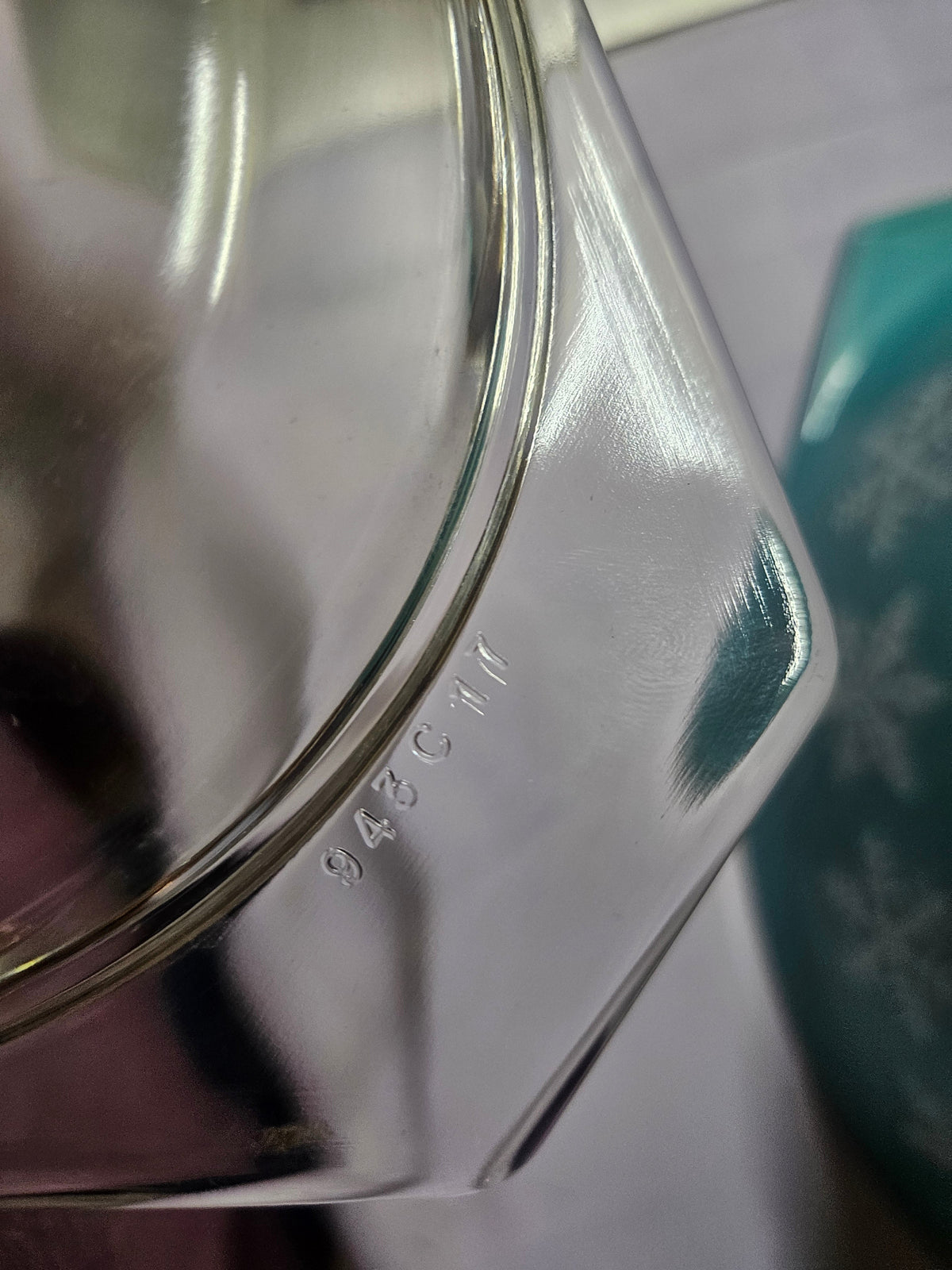 Two turquoise Pyrex casseroles with white snowflake design stacked together, the smaller one topped with a clear glass lid