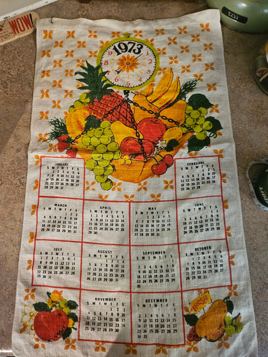 1973 fruit basket scale calendar tea towel showing pineapple, grapes, cherries, and full 12-month calendar grid