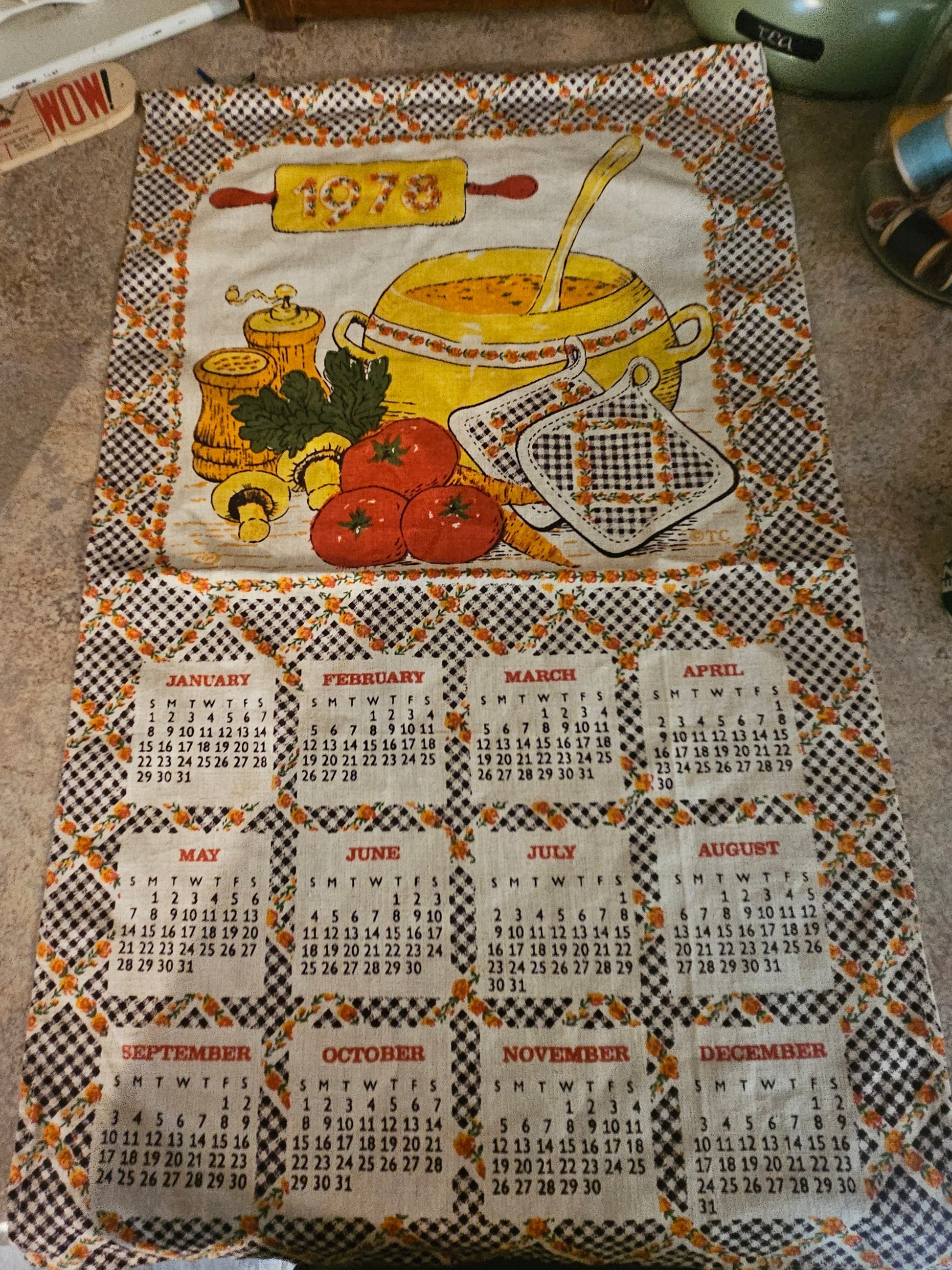 1973 soup pot kitchen calendar tea towel showing Dutch oven, tomatoes, gingham border, and 12-month calendar grid