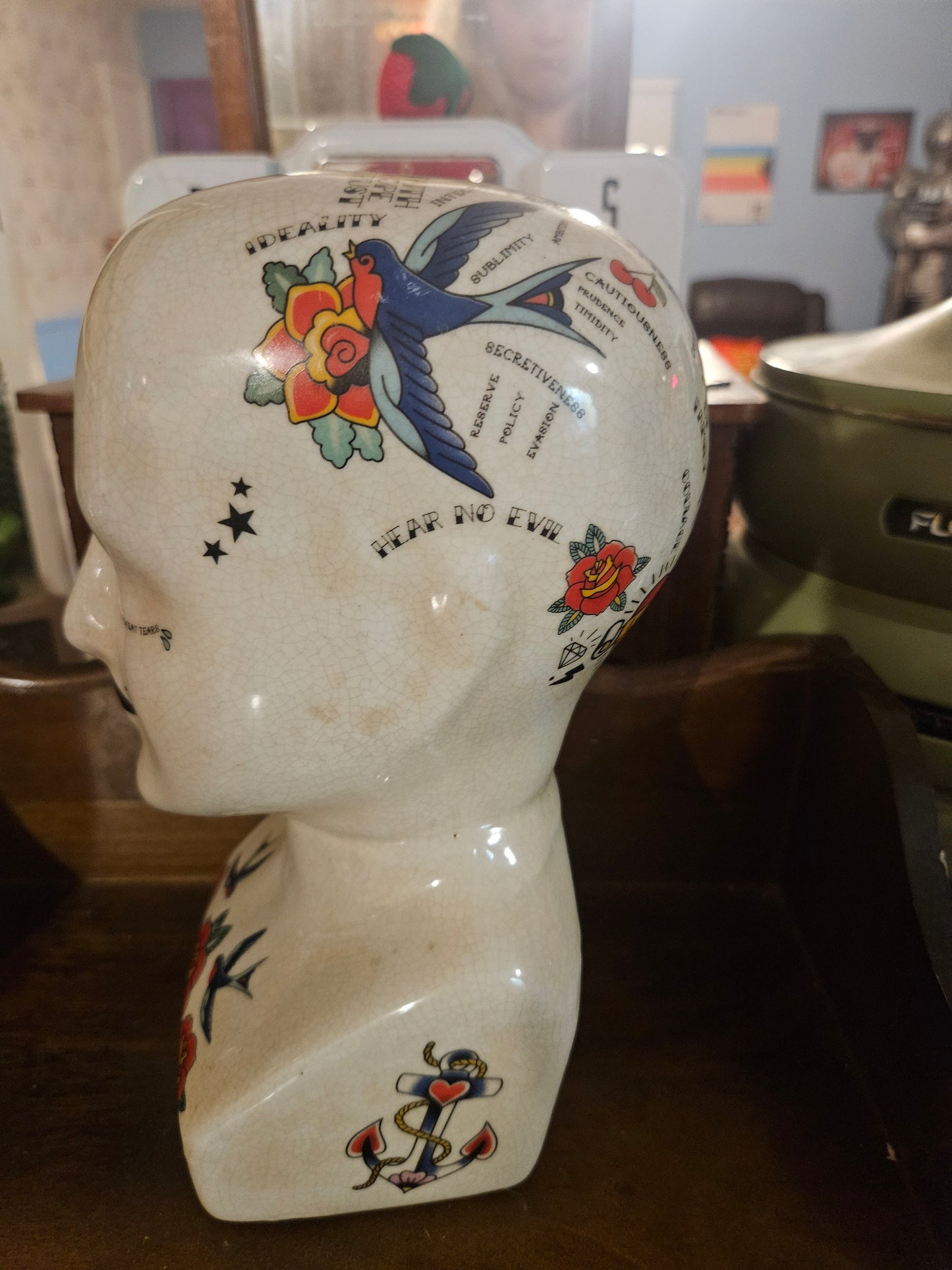 Other side of ceramic phrenology head planter showing Hear No Evil text swallow rose and anchor tattoo art