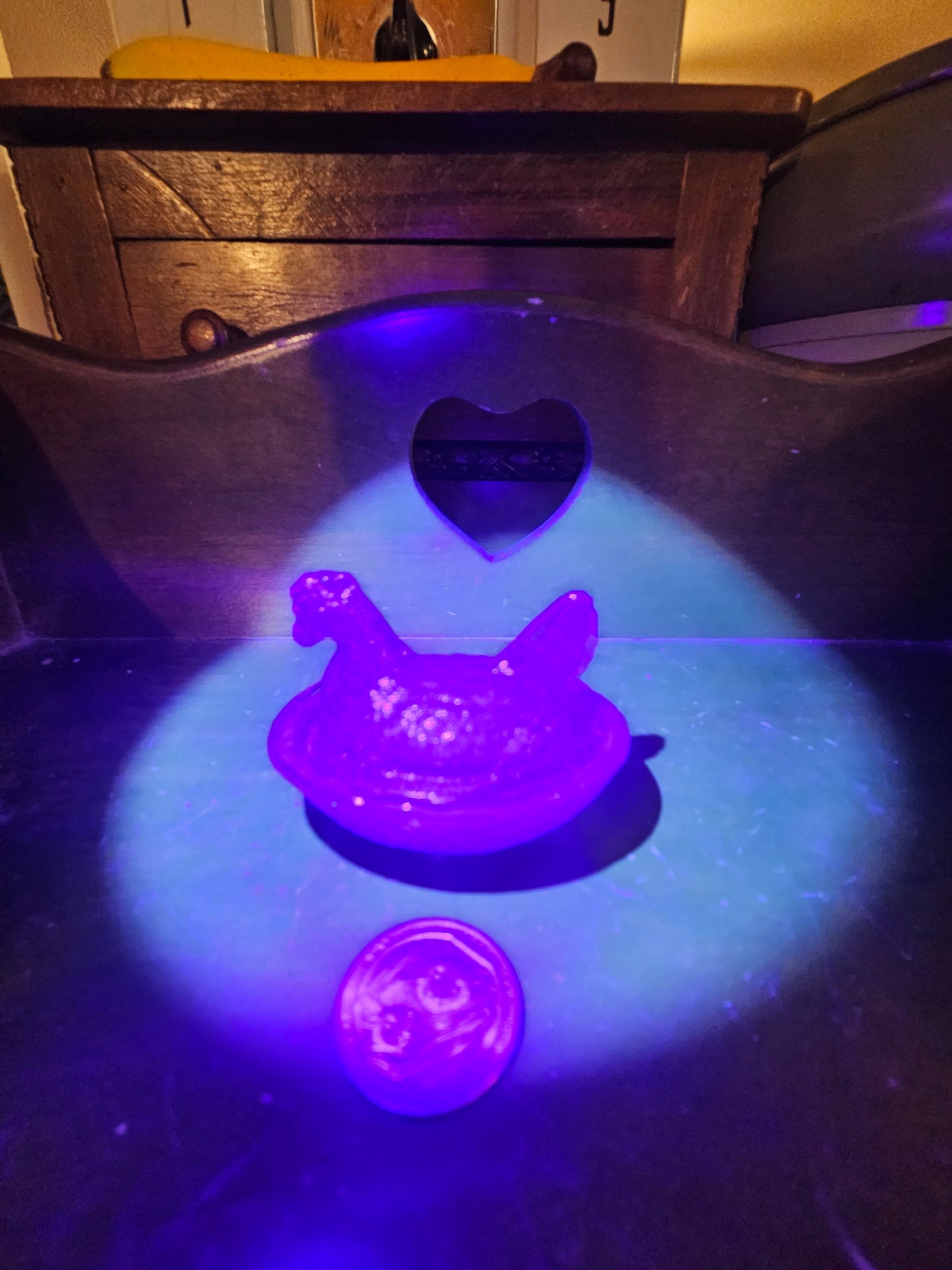 Pink opalescent glass hen on nest glowing vivid purple under UV blacklight