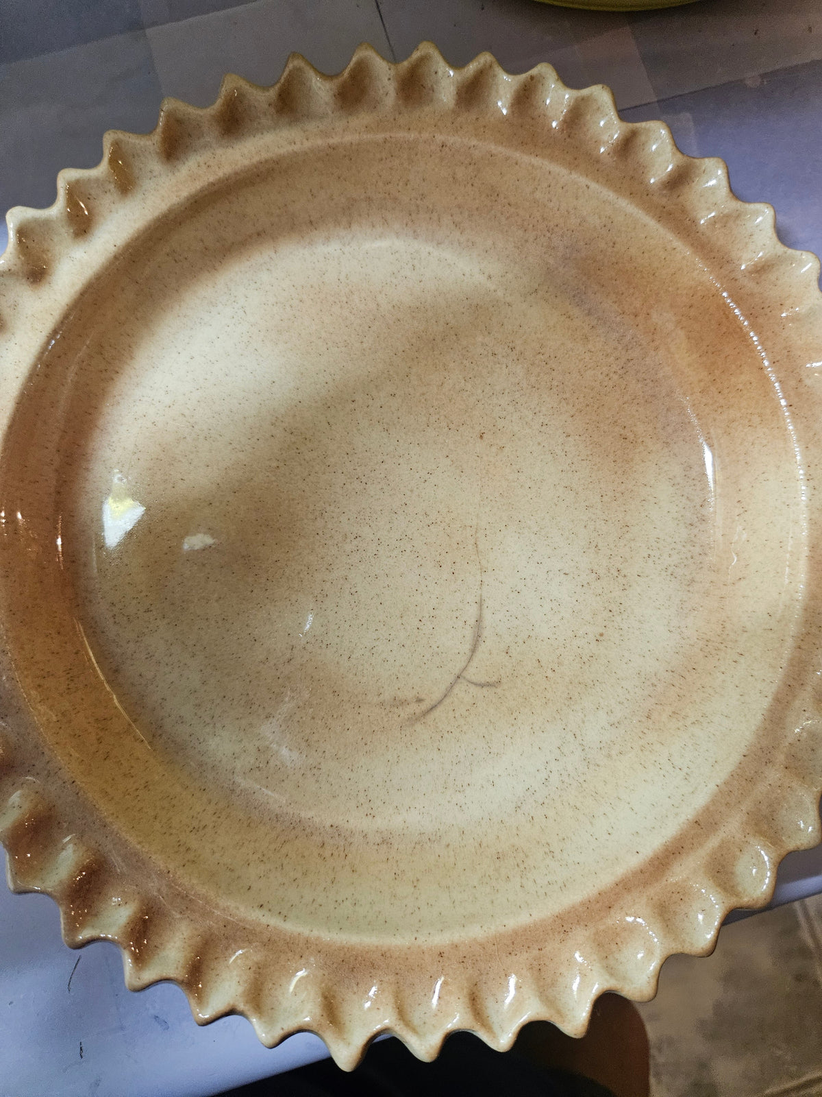 Top view of ceramic cherry pie keeper lid showing red lattice pattern and sculpted cherry with green leaf finial