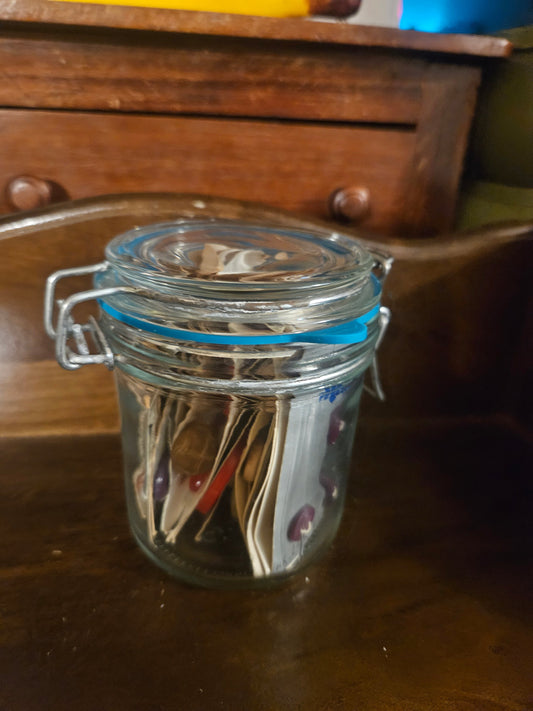 Swing-top glass jar filled with vintage button cards, closed view