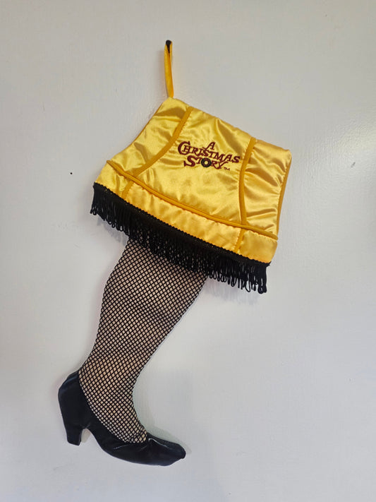 A Christmas Story Leg Lamp Christmas stocking front view showing gold satin shade with embroidered logo, black fringe, fishnet leg and black heel